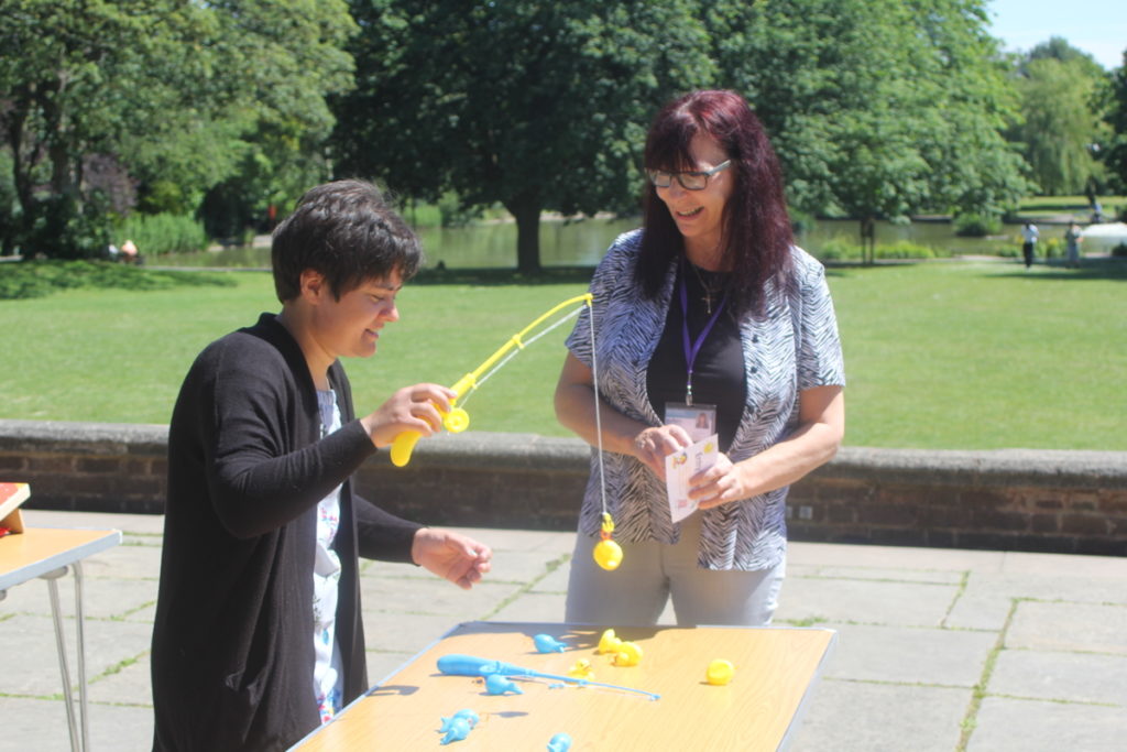 autistic lady playing hook a duck with support worker