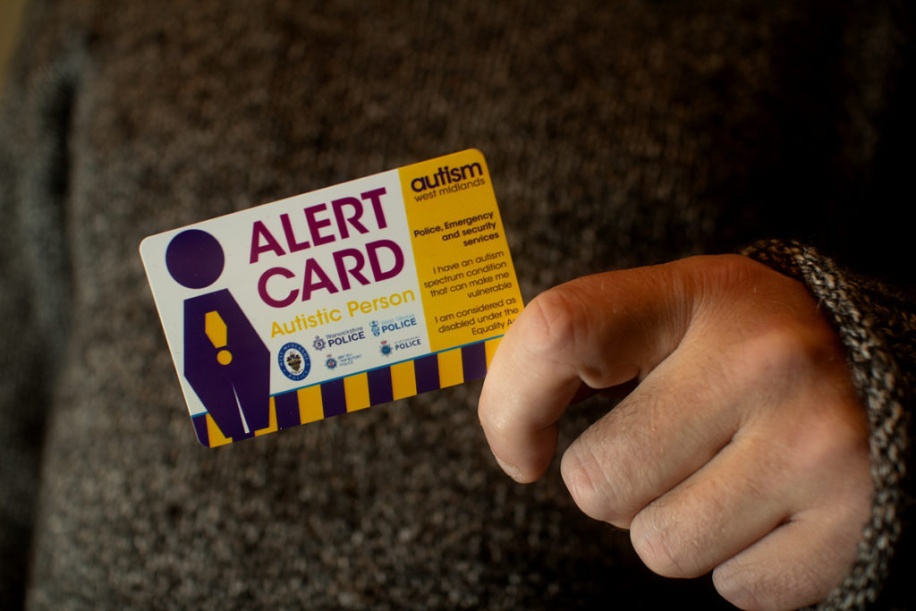 Someone holding an Autistic Person Alert Card